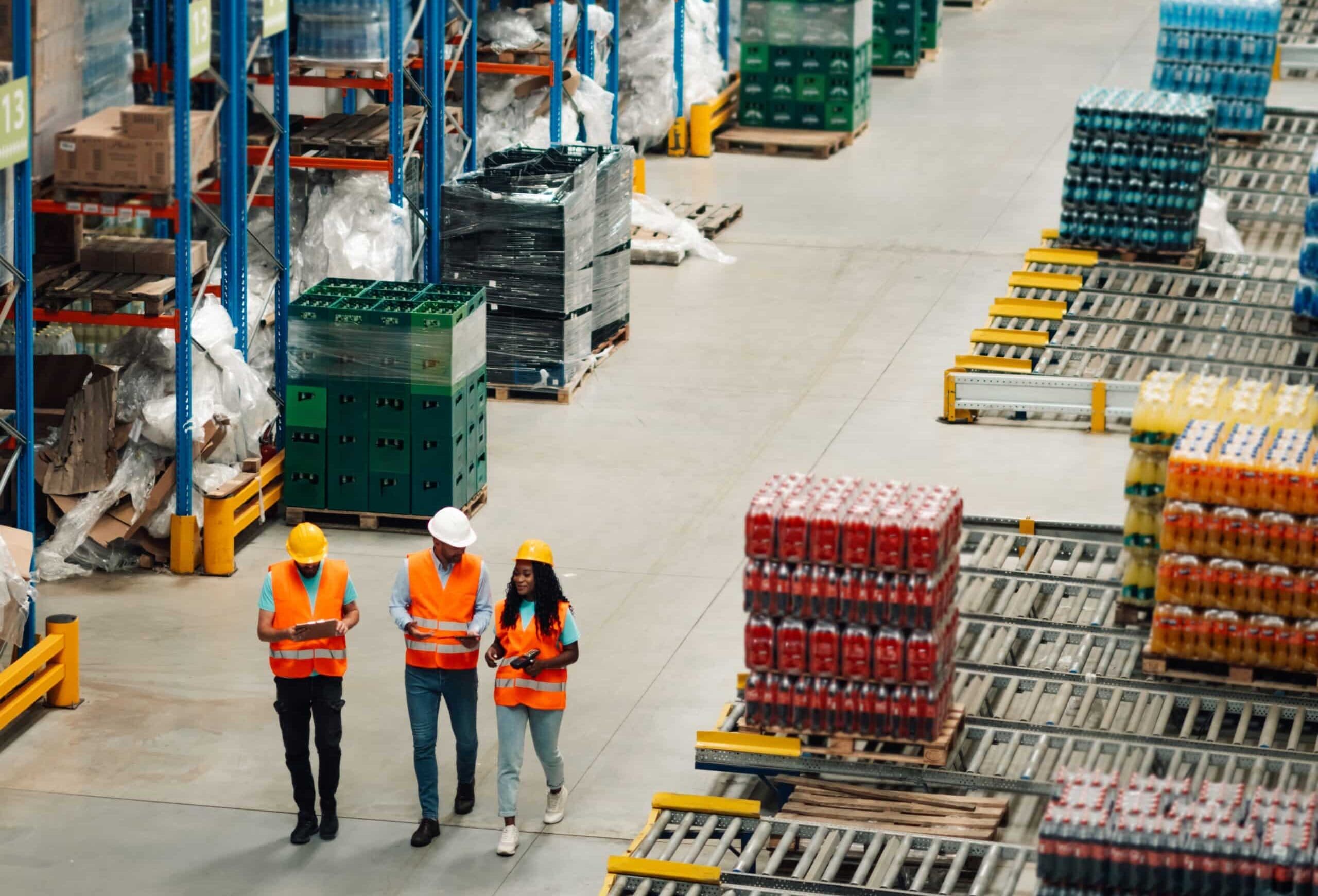 Three,Warehouse,Workers,In,Safety,Vests,And,Helmets,Are,Walking